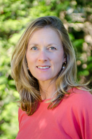 A woman in a pink shirt is smiling for the camera.