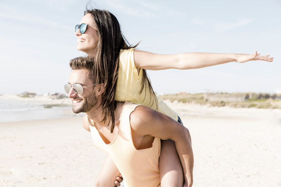 A man and woman are playing on the beach.
