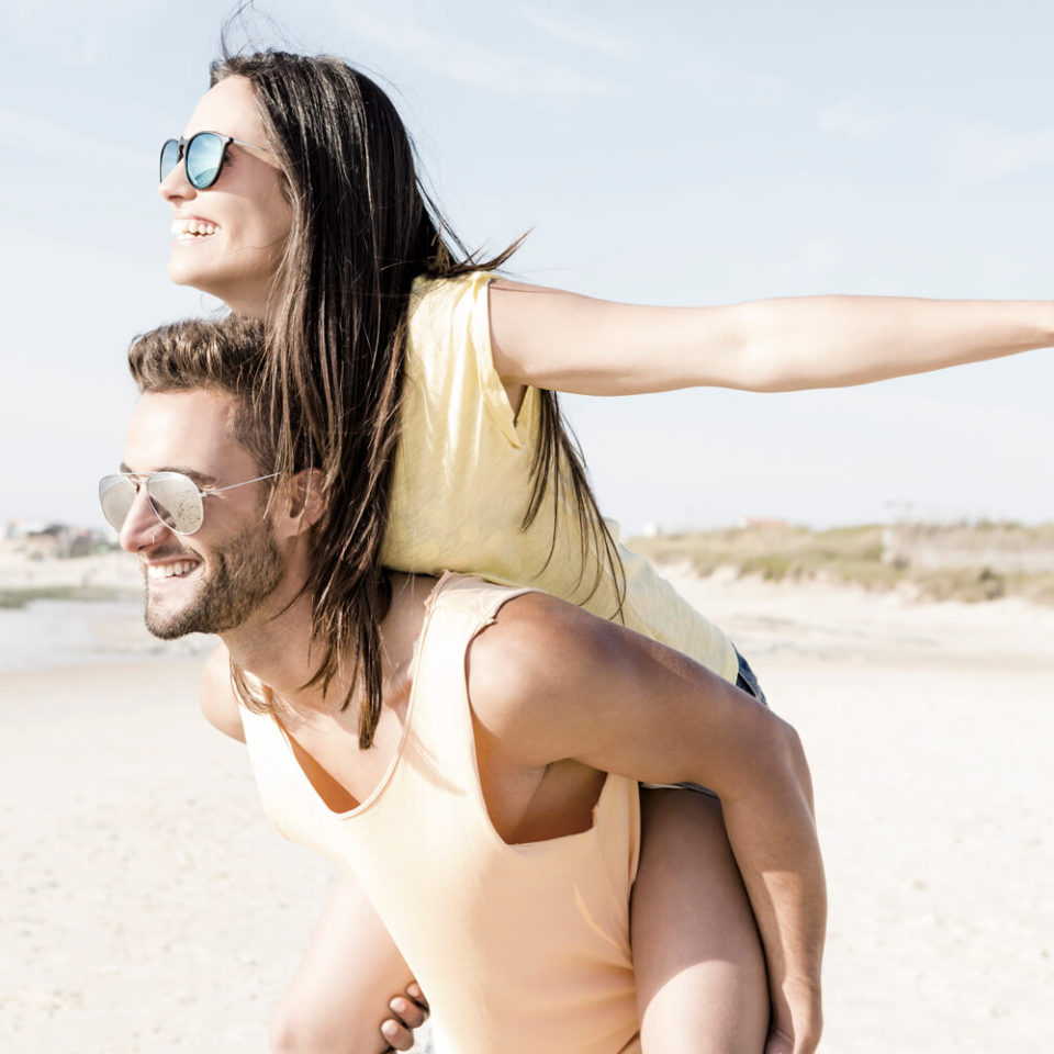 A man and woman are playing on the beach.