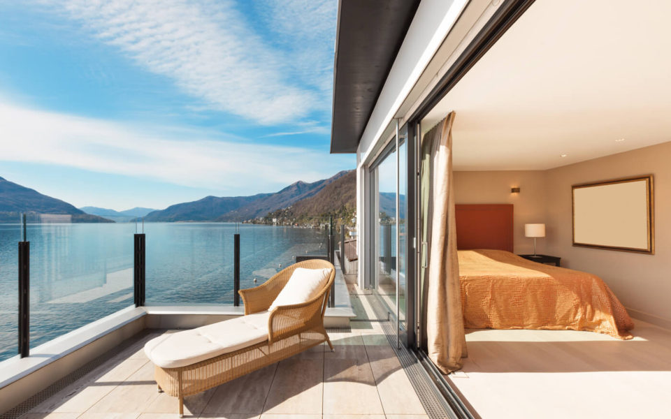 A balcony with a view of the ocean and mountains.