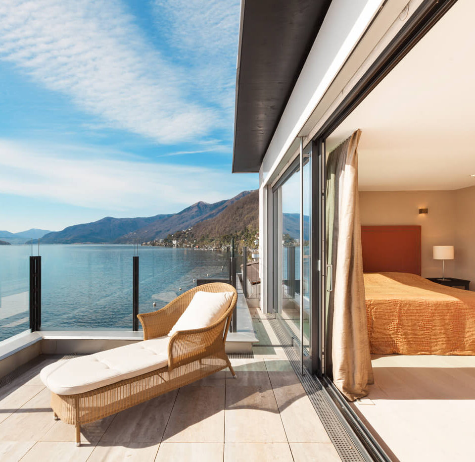 A balcony with a view of the ocean and mountains.