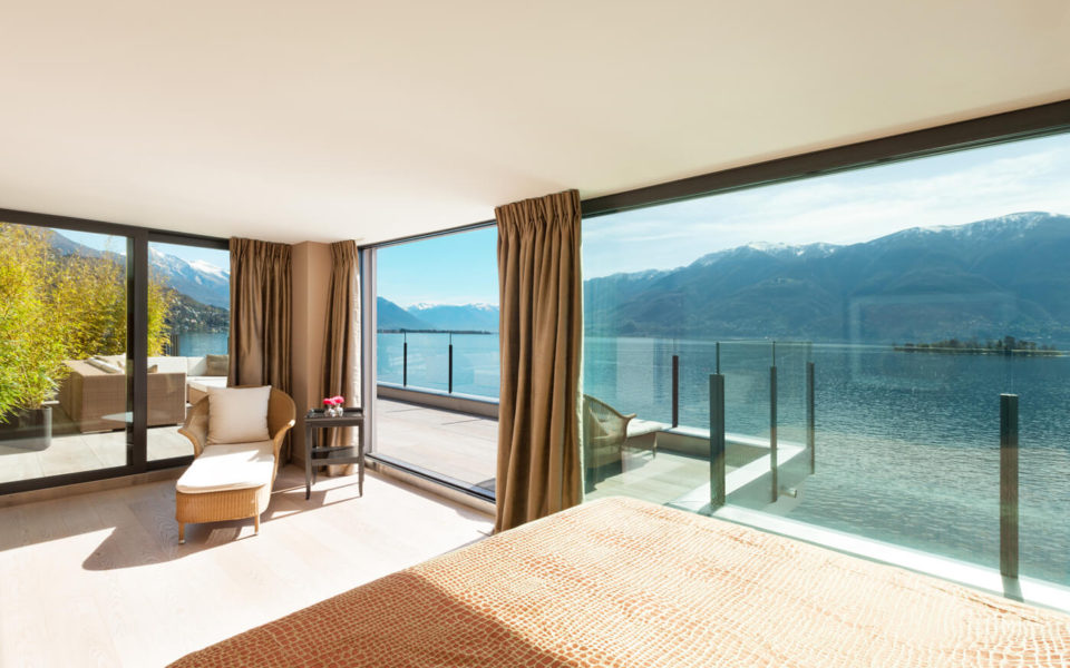 A bedroom with a large window overlooking the water.