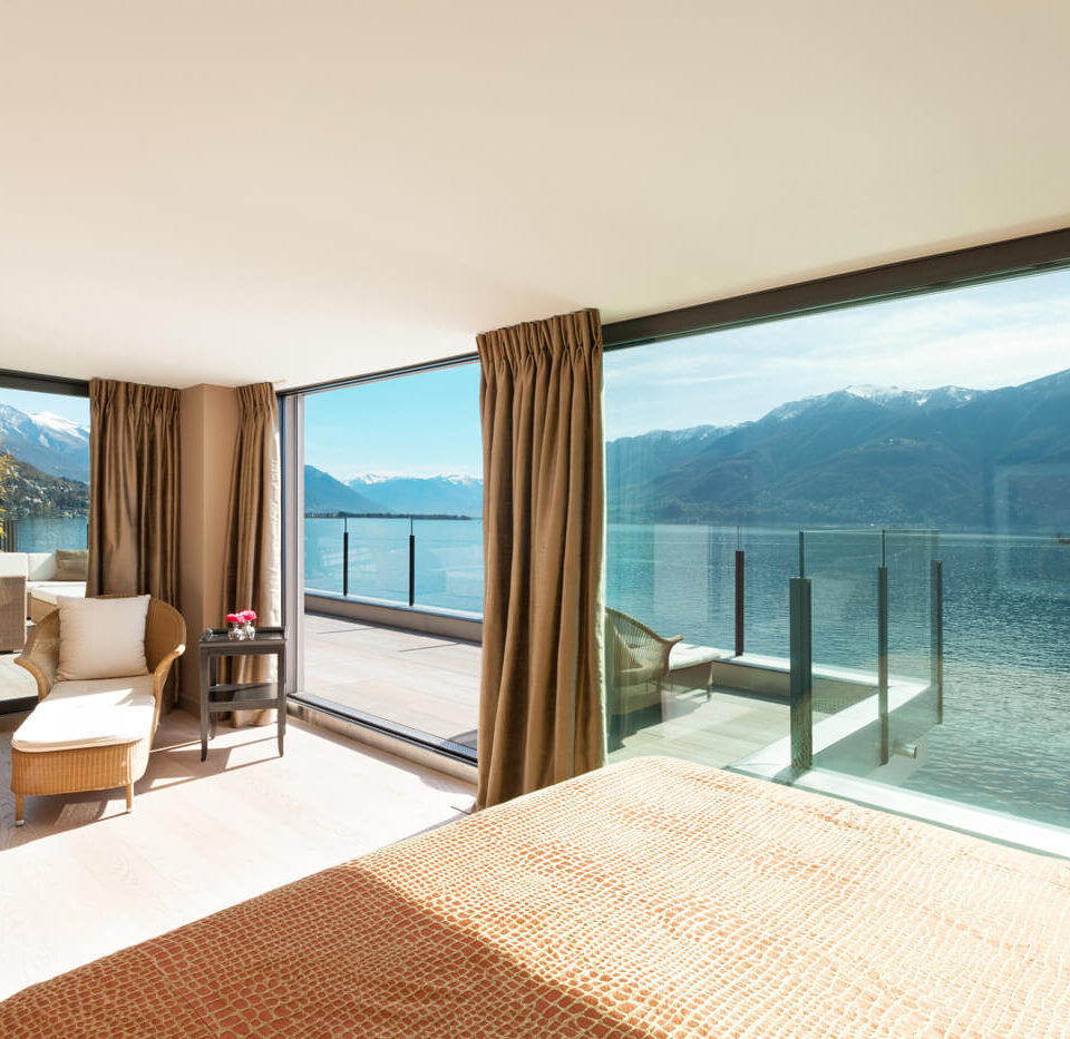 A bedroom with a large window overlooking the water.