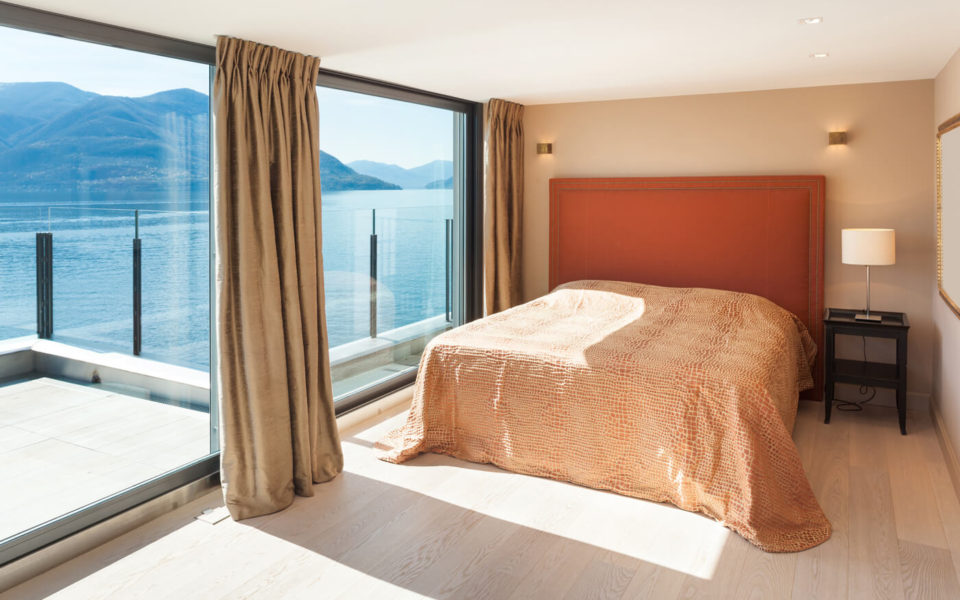 A bed room with a large window and a view of the water