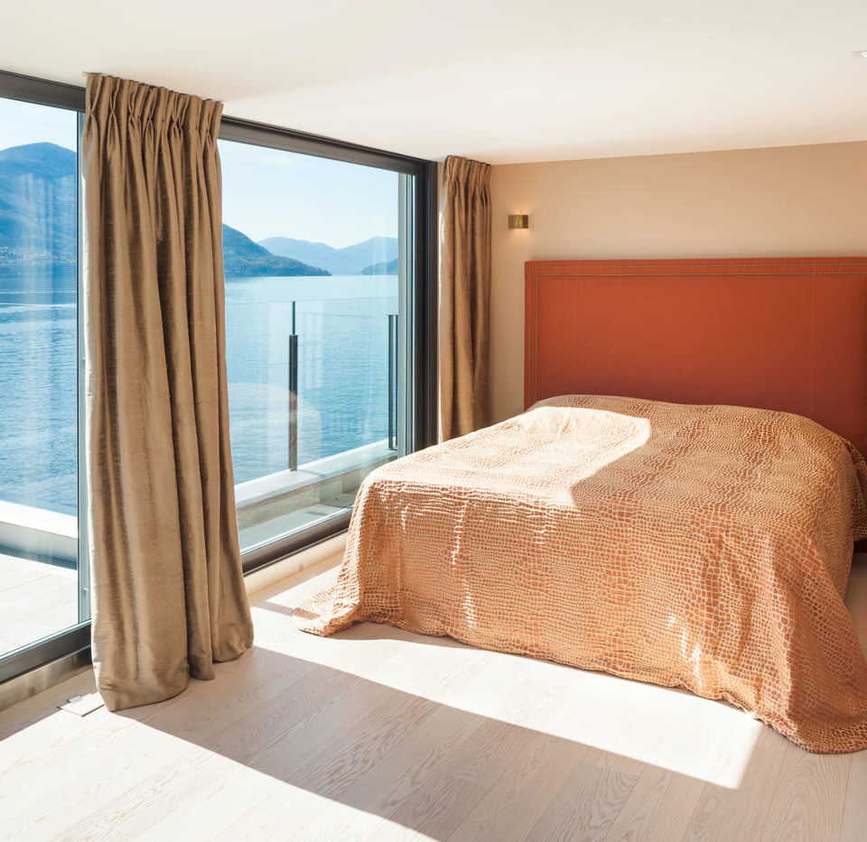 A bed room with a large window and a view of the water