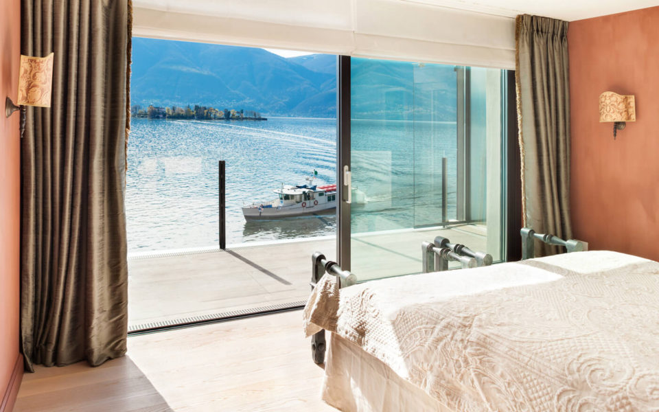 A bedroom with a view of the water and mountains.