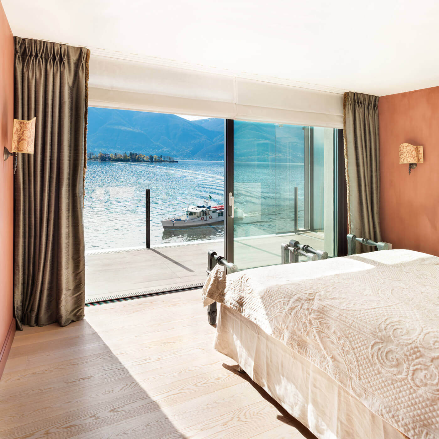A bedroom with a view of the water and mountains.