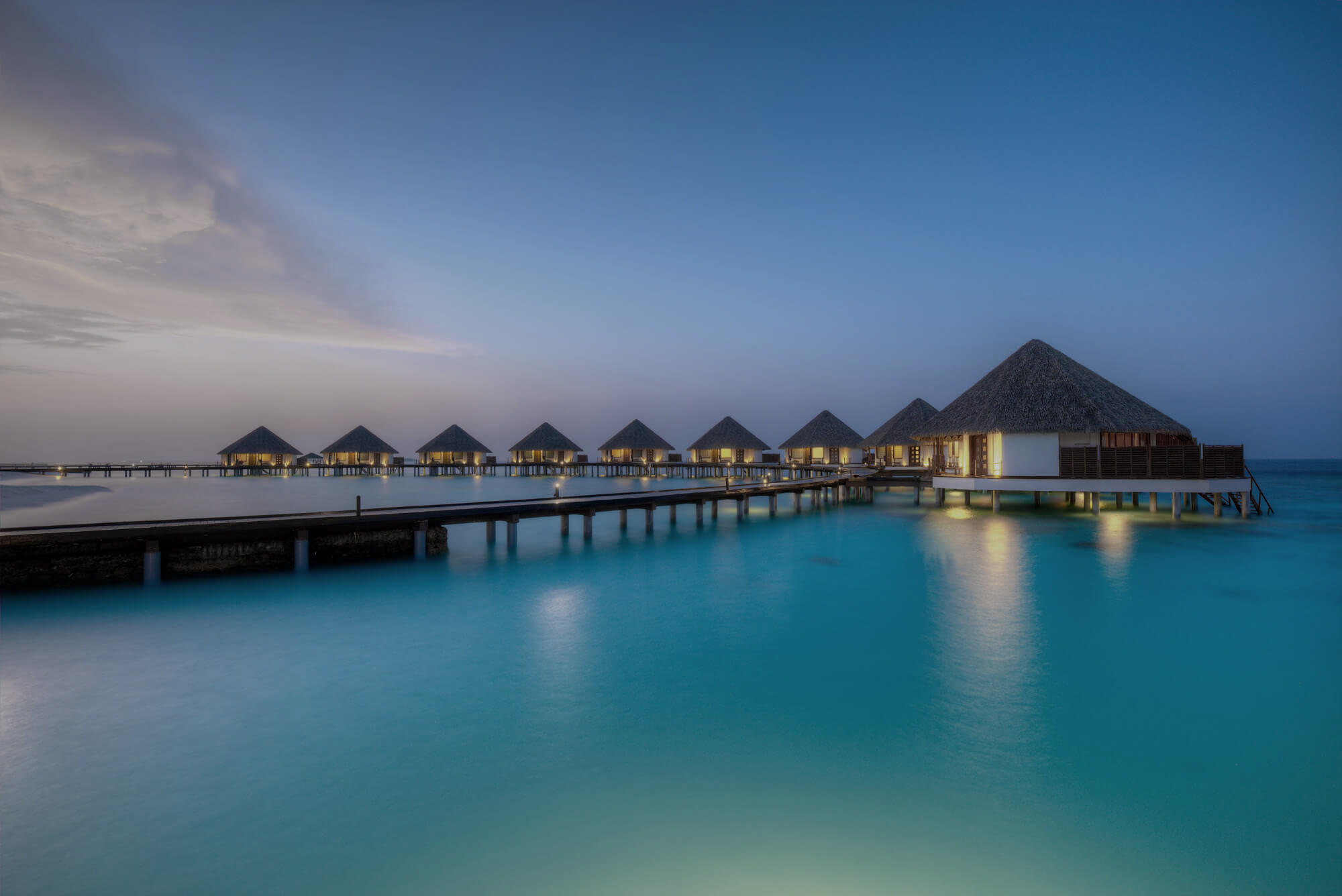 A long row of wooden huts on stilts over water.