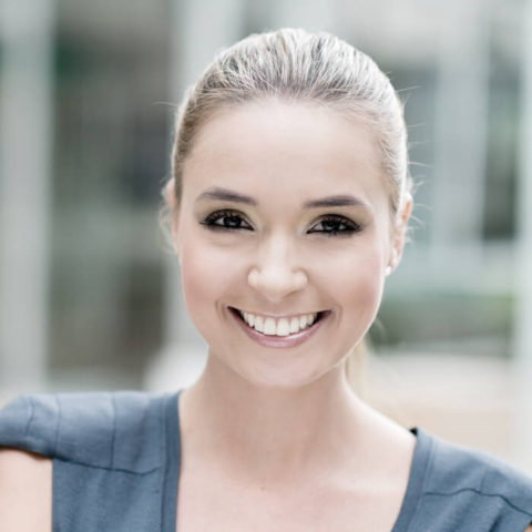 A woman with blonde hair and blue eyes smiling.