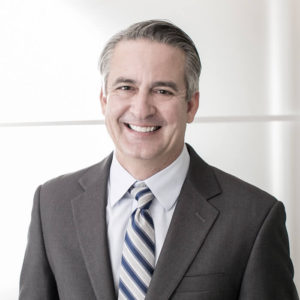 A man in suit and tie smiling for the camera.