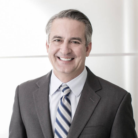 A man in suit and tie smiling for the camera.