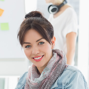A woman with a scarf and a bun is smiling.